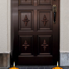 Dark wooden door with decorative panels and candles on a blue tiled floor.