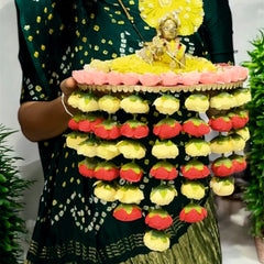 Person holding a colorful flower arrangement with a small statue on top