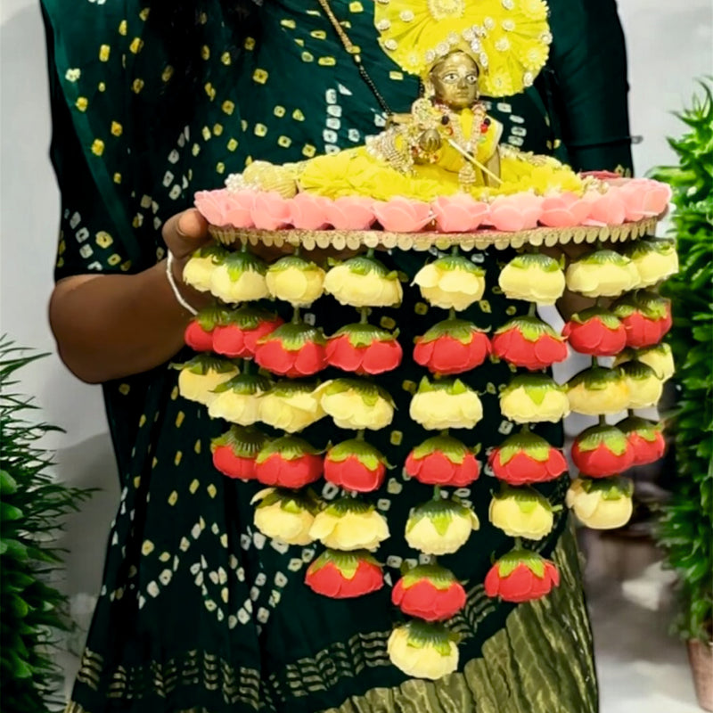 Person holding a colorful flower arrangement with a small statue on top