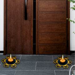Wooden door with two lit candles on a stone floor, one with a decorative metal holder.
