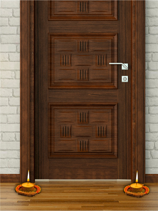 Wooden door with decorative patterns, two lit candles on either side, and a light gray brick wall background.