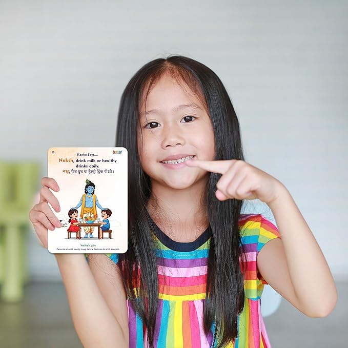 Young girl holding a book with a colorful cover, pointing to her teeth.