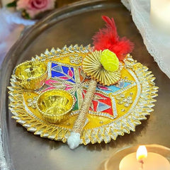Decorative plate with gold elements and colorful design on a tray with candles and flowers.