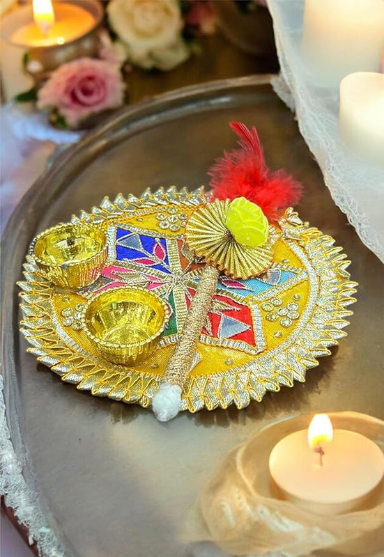 Decorative plate with gold elements and colorful design on a tray with candles and flowers.