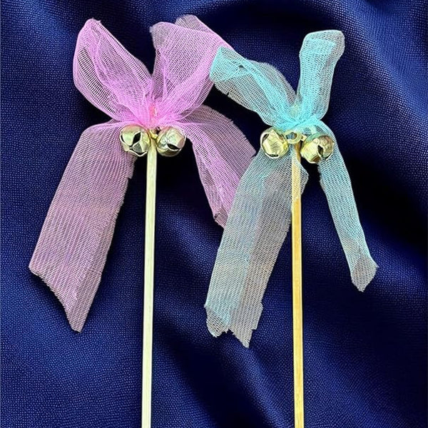 Two decorative hair sticks with pink and blue ribbons on a dark blue fabric background