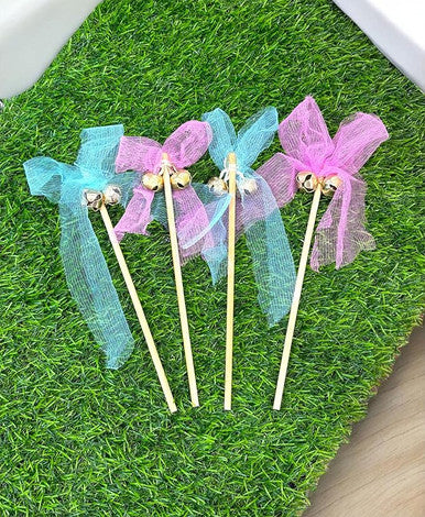 Three decorative sticks with ribbons on a green grass-like surface