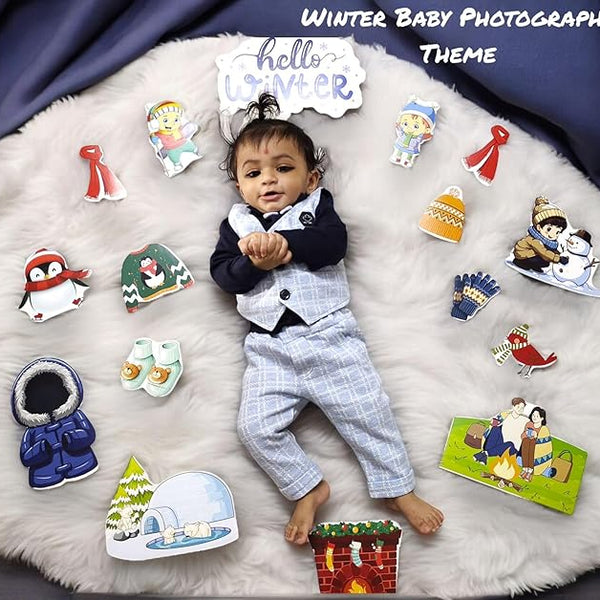 Baby in a winter-themed outfit surrounded by winter-themed props on a fluffy white surface.