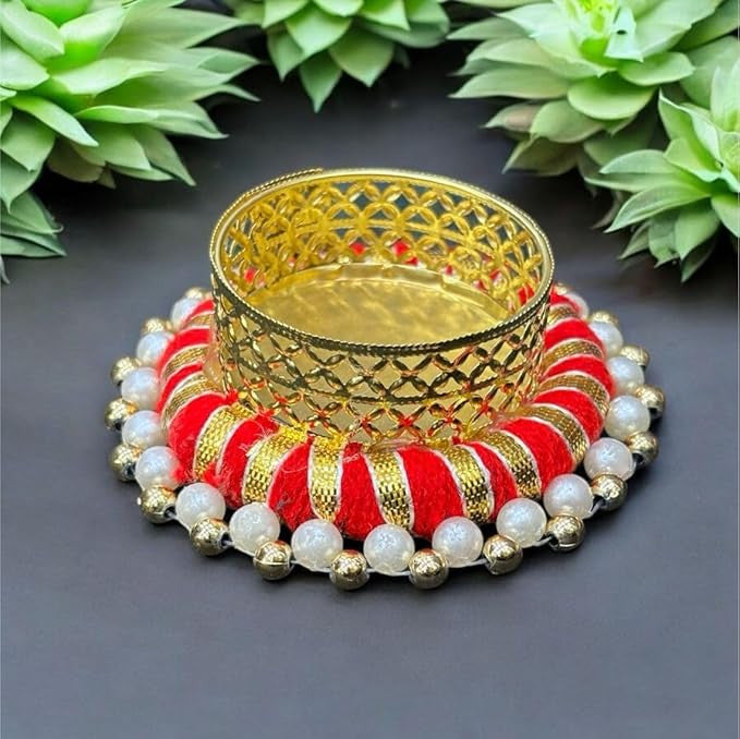 Decorative gold, red, and pearl jewelry set on a dark surface with green plants in the background.