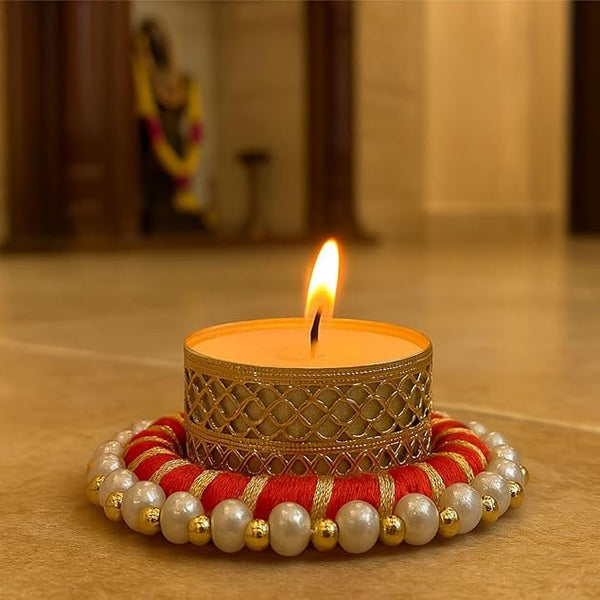 Decorative candle with a gold holder and red and gold base on a wooden surface.