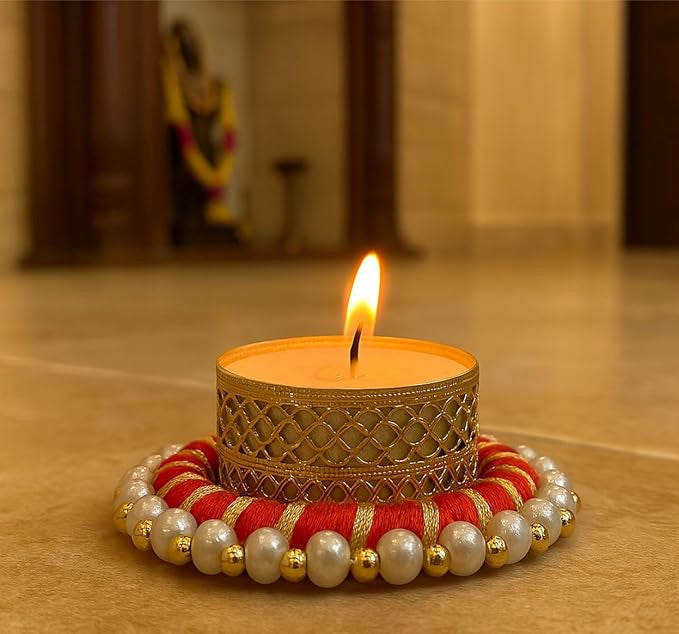Decorative candle with a gold holder and red and gold base on a wooden surface.