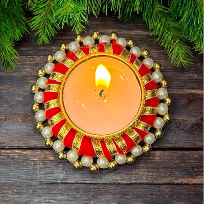 Decorative candle holder with a lit candle on a wooden surface with greenery around.