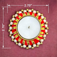 Decorative candle holder with red, gold, and pearl design on a pink background