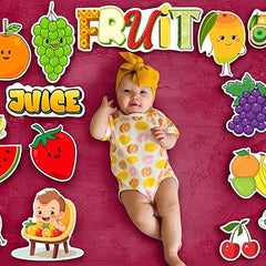 Baby in a onesie surrounded by fruit-themed stickers on a red background