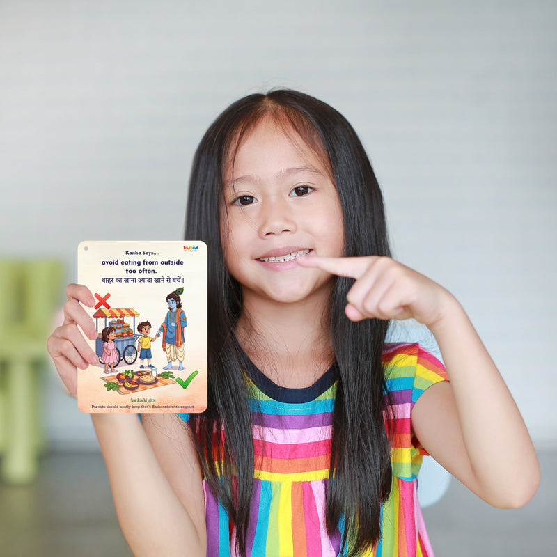 Young girl pointing to a colorful educational card held in her hand.