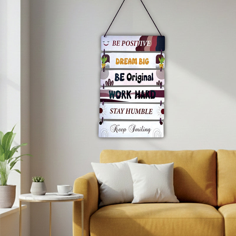 Decorative wall sign with motivational phrases above a yellow sofa in a living room.