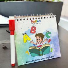 Children's book with alphabet illustrations and a magic pen on a desk with plants in the background