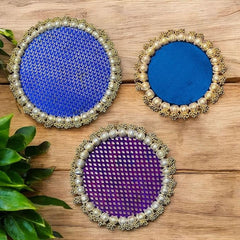 Three decorative coasters with blue, purple, and gold patterns on a wooden surface.