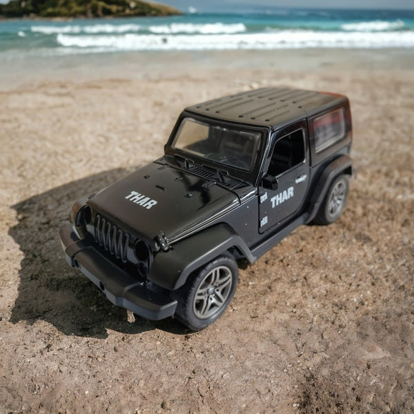 Black toy jeep on a sandy beach with ocean waves in the background