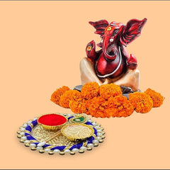 Decorative item with a red and gold elephant figure, marigold flowers, and a small tray on a beige background.