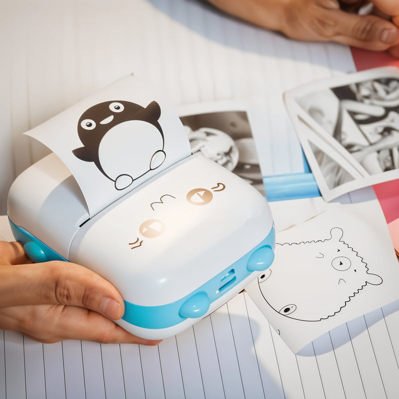 Small printer with cartoon design on a piece of paper, held by a person.