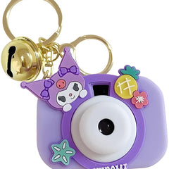 Purple camera-shaped keychain with cartoon character and bell on a white background