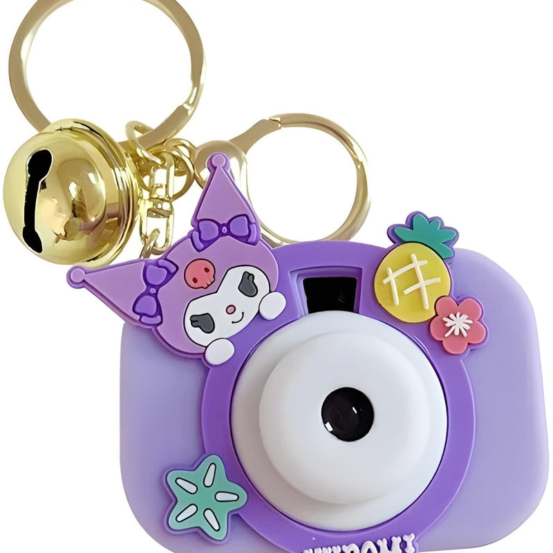 Purple camera-shaped keychain with cartoon character and bell on a white background