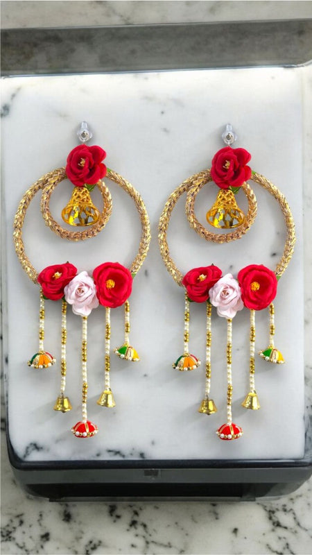 Decorative earrings with red and pink flowers on a marble surface
