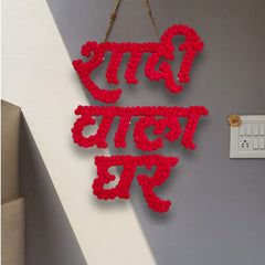 Red crochet wall art with text on a gray wall