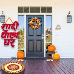 Decorative setup with pumpkins, wreath, and text on a front door