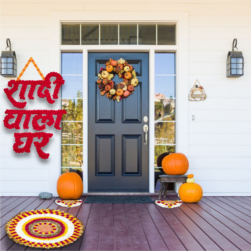 Decorative setup with pumpkins, wreath, and text on a front door