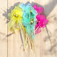 Colorful party wands with ribbons and bells on a wooden surface