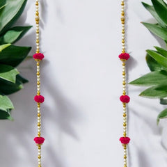 Pink and gold beaded earrings with leafy green plants in the background