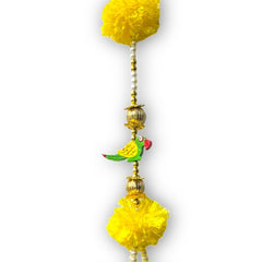 Decorative hanging with yellow pom-poms and a small bird figurine on a white background