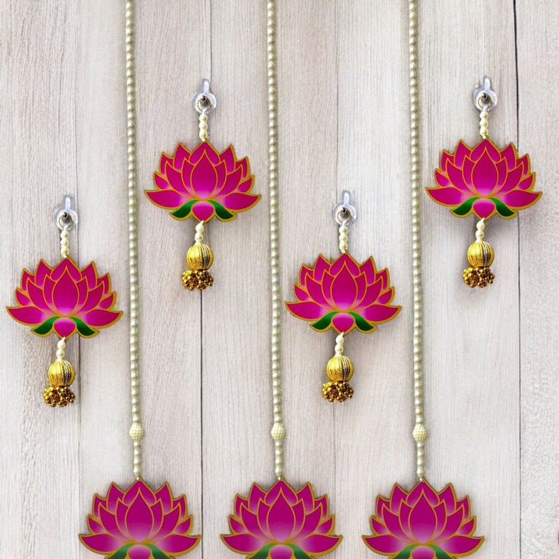 Set of pink lotus-shaped hanging decorations with gold accents on a wooden background