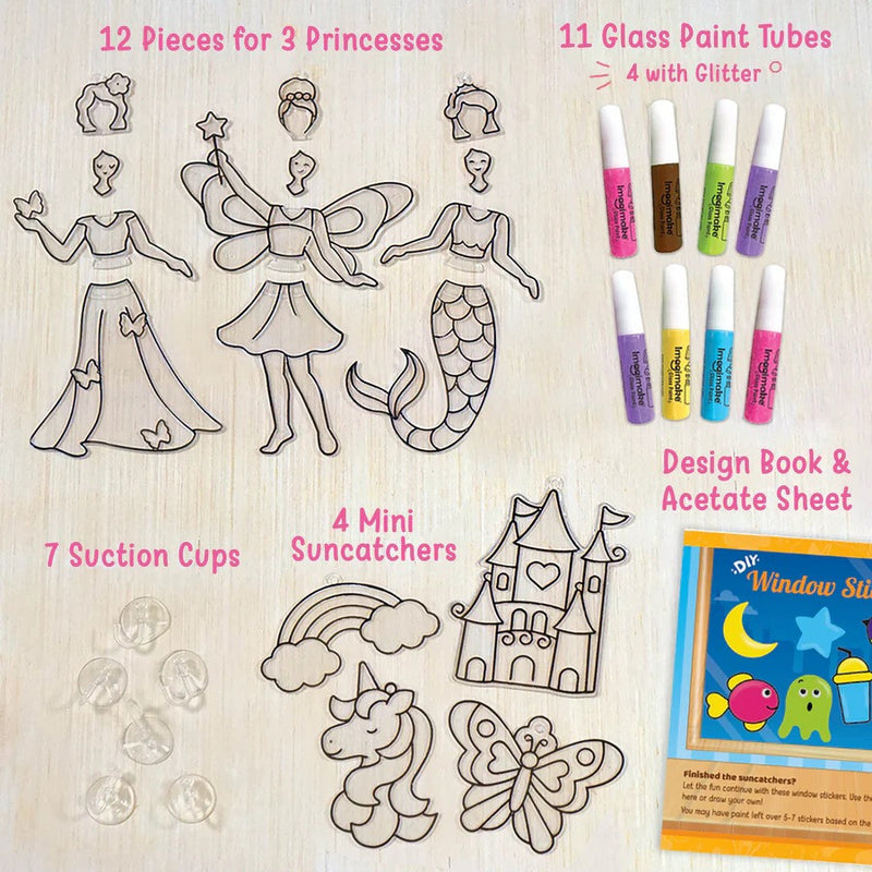Set of window stickers with princess, mermaid, unicorn, and castle designs, along with glass paint tubes and a design book on a wooden surface.